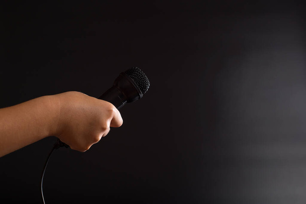 Child handholding black microphone close up, on black background with copy space. - Φωτογραφία, εικόνα