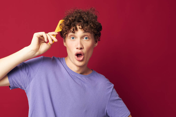 portrait of a young curly man posing hairbrush personal care Youth style - Fotoğraf, Görsel