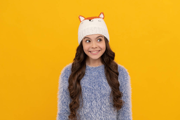 glückliches Kind lange Haare in Hut auf gelbem Hintergrund, Winter - Foto, Bild