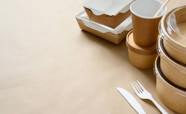Jednorazowa biodegradowalna tekturowa zastawa stołowa. Papierowe kubki i pojemniki na żywność na papierze rzemiosła. Wybiórcze skupienie. Puste miejsce po lewej dla tekstu. - Zdjęcie, obraz