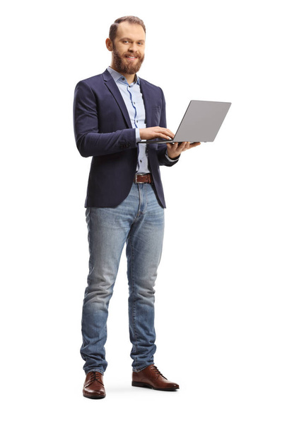 Full length portrait of a man in a suit and jeans holding an open laptop computer isolated on white background - Photo, image
