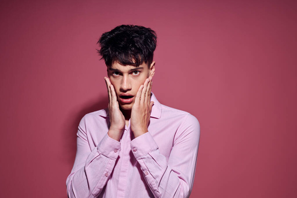 pretty man in a pink shirt gesturing with his hands pink background unaltered - Foto, immagini