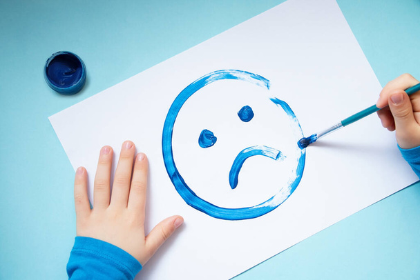 Top view of the child hands, drawing sad face.Kék hétfő és mentális egészség koncepció. - Fotó, kép