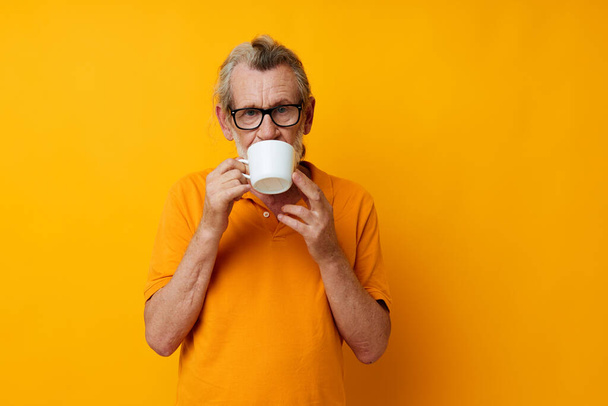 Photo of retired old man in a yellow t-shirt white mug monochrome shot - Foto, afbeelding