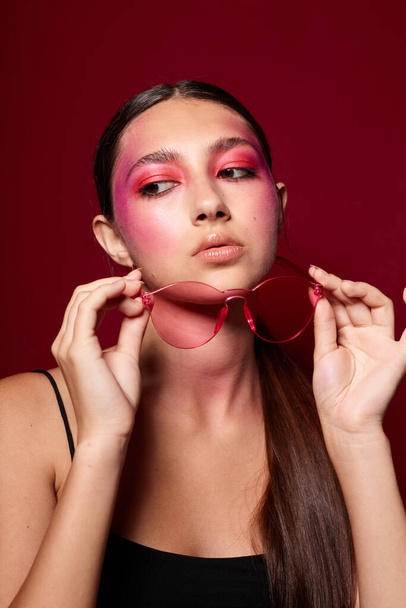 Portrait of beautiful young woman bright makeup posing fashion emotions fashion glasses pink background unaltered - Φωτογραφία, εικόνα