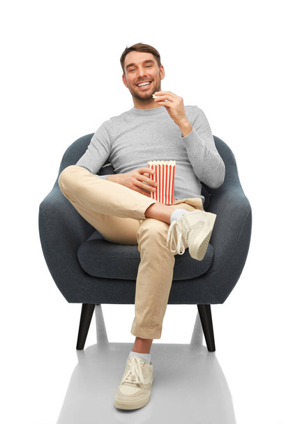 smiling man eating popcorn sitting in chair - Φωτογραφία, εικόνα