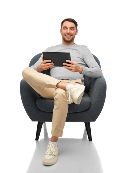 smiling man with tablet computer sitting in chair - Φωτογραφία, εικόνα