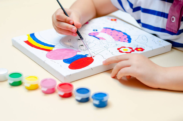 Ulyanovsk, Russia, January, 20, 2022: A five-year-old girl paints a sketch-painting by numbers with colored paints. Blurry, defocused, selective focus - Foto, afbeelding