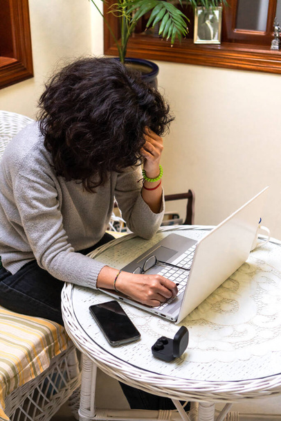 Από πάνω αγνώριστη κουρασμένη ελεύθερη επαγγελματίας γυναίκα με σγουρά σκούρα μαλλιά αγγίζοντας το μέτωπο, ενώ εργάζονται εξ αποστάσεως σε φορητό υπολογιστή στο καφέ - Φωτογραφία, εικόνα