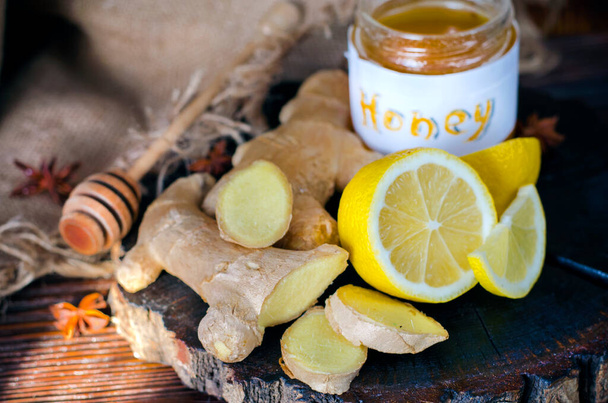 Honey, ginger root and lemon on a wooden board. Folk antiviral remedy - Foto, imagen