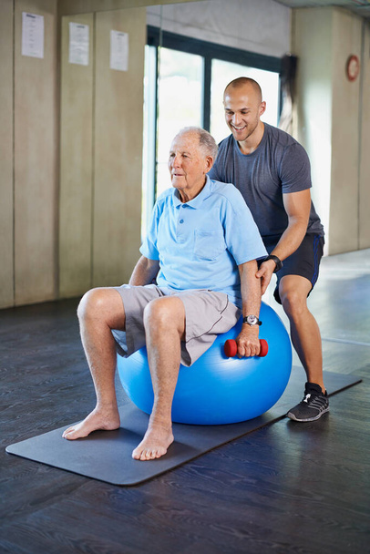 Just one more lift. Cropped shot of a handsome personal trainer with a senior man. - Foto, Imagen