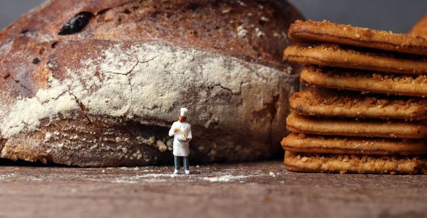 Pan tostado y un chef en miniatura. Personas en miniatura y concepto de negocio. - Foto, Imagen
