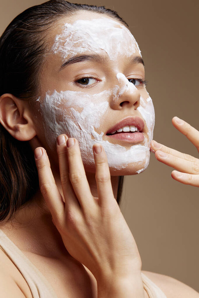 vrouw gezicht masker crème schone huid gezicht scrub beige achtergrond - Foto, afbeelding