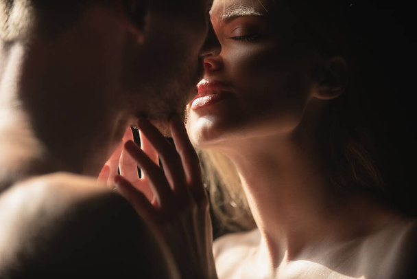 Sensual woman lips in the tender passion. Romantic couple in love looking at each other, embracing and kissing on black background. - Φωτογραφία, εικόνα