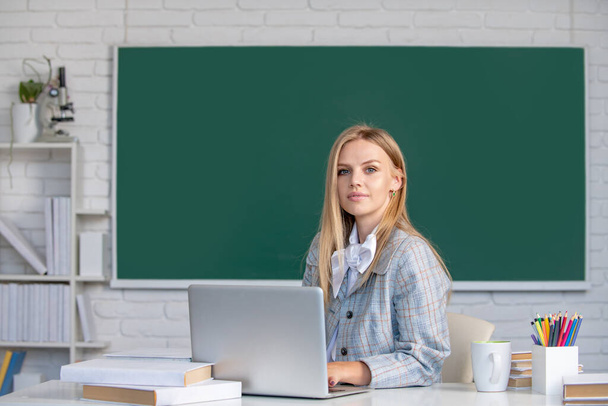 Young teacher. Portrait of young female college student studying in classroom on class with blackboard background. - Foto, Imagem