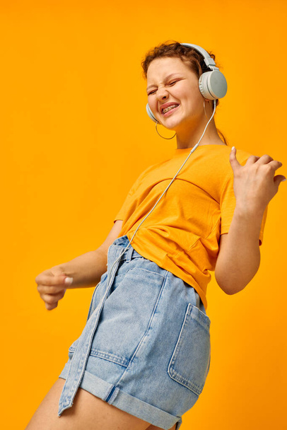 pretty woman yellow t-shirt headphones entertainment music fun yellow background unaltered - Фото, изображение