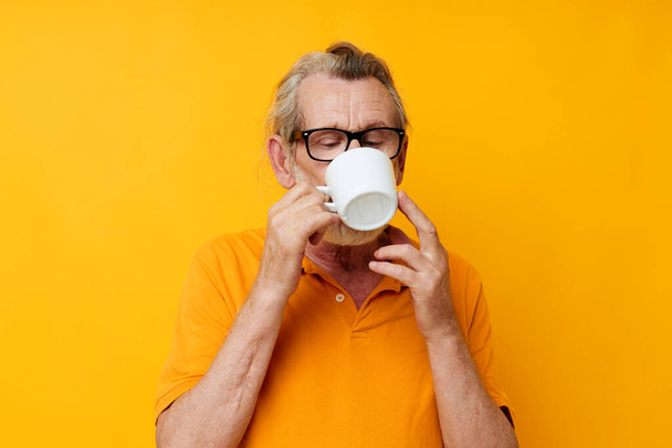 Photo of retired old man in a yellow t-shirt white mug monochrome shot - Valokuva, kuva