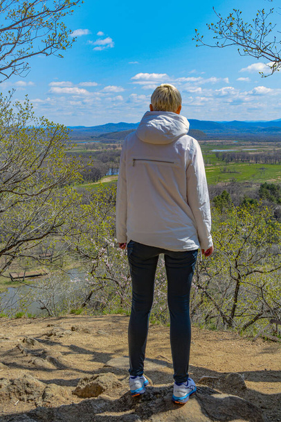 Μια γυναίκα στέκεται σε ένα λόφο μπροστά από μια όμορφη κοιλάδα - Φωτογραφία, εικόνα