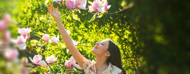 Spring woman face for banner. Young girl on Spring flowers background. Magnolia. Beautiful young woman with blossom branch, young woman in spring blossom garden. - Φωτογραφία, εικόνα