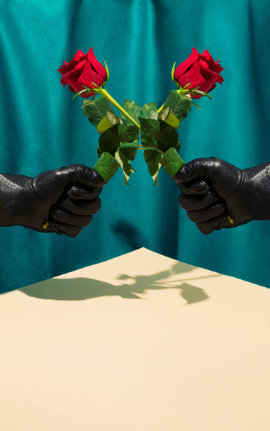 Minimalna scena w stylu retro z czarnymi rękawiczkami trzymającymi kwiat czerwonej róży nad jasnym, piaszczystym stołem i zieloną, jedwabną kurtyną. Retro Walentynki strona koncepcja. - Zdjęcie, obraz