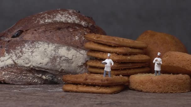 İki minyatür şef çıtır kurabiyeyle ayakta duruyor. Minyatür insanlar ve iş konsepti. - Video, Çekim