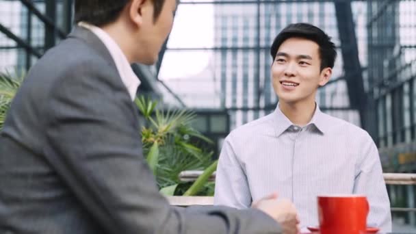 deux asiatiques hommes d'affaires assis parler discuter en plein air café - Séquence, vidéo