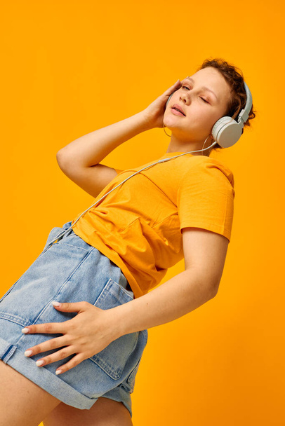 pretty girl summer style headphones dance yellow background unaltered - Foto, Imagen