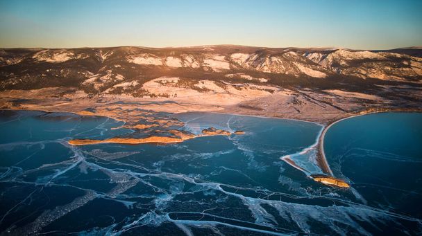 View of the frozen Lake Baikal in January. Transparent ice with cracks. Kurma Bay, Cape Uyuga from the air - Foto, imagen