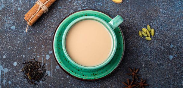 Ινδικό τσάι ζεστό ρόφημα με γάλα και μπαχαρικά σε ρουστίκ πράσινο τσάι με συστατικά για την παρασκευή masala chai - Φωτογραφία, εικόνα
