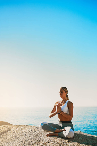 I am whole in myself. Shot of an athletic young woman practicing yoga on the beach. - Foto, afbeelding