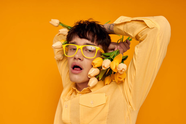 Photo of romantic young boyfriend with a fashionable hairstyle in yellow shirts with flowers yellow background unaltered - 写真・画像
