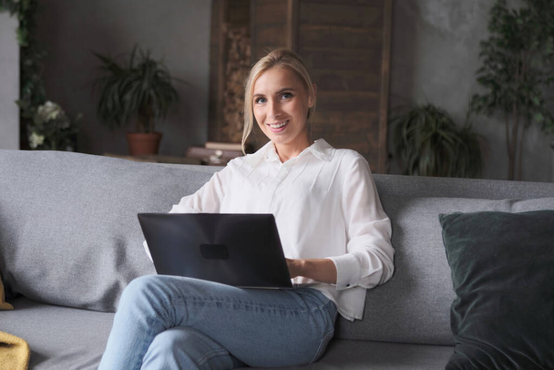 Freelancer mulher jovem pensativo digitando no sofá sentado laptop. - Foto, Imagem