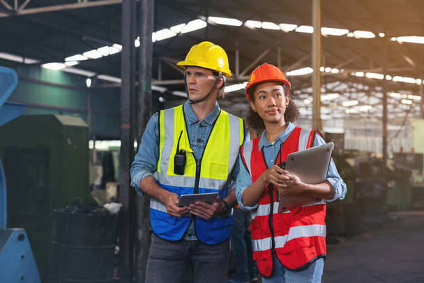 Een portret van een fabrieksarbeider in gesprek met een industrieel man en vrouw ingenieur die een tablet in een fabriek vasthoudt. Een blanke voorman staat onder toezicht van een CNC-machine.. - Foto, afbeelding