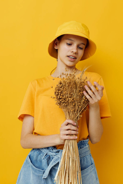 young beautiful woman a bouquet of dried flowers in hands Youth style casual wear yellow background - Φωτογραφία, εικόνα