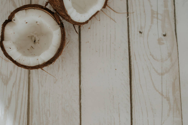 Two halves of a coconut lie on a wooden floor. Coconut fruits lie on a white wooden background. Place for text. Selectiv focus - Foto, immagini