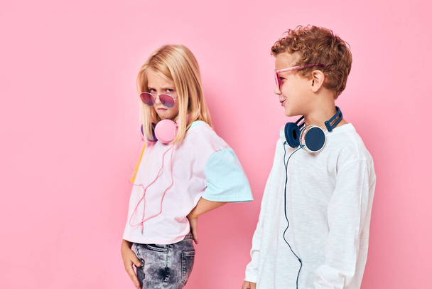 Ευτυχισμένο παιδί ζευγάρι φορώντας ακουστικά που θέτουν ροζ χρώμα φόντο - Φωτογραφία, εικόνα