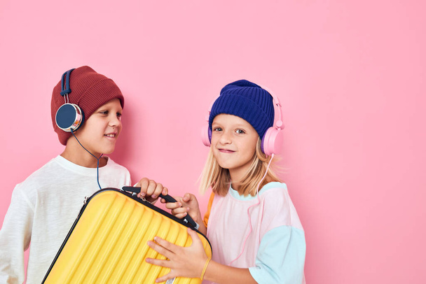 чарівні маленькі діти жовта валіза з навушниками рожевого кольору фону
 - Фото, зображення