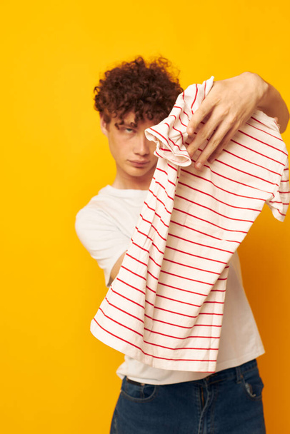 cute red-haired guy in a white t-shirt holds a striped t-shirt fashion youth style isolated background unaltered - 写真・画像