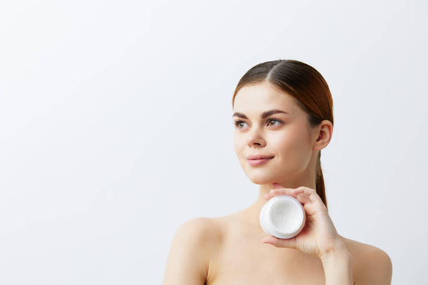 mujer joven crema corporal posando cuidado de la piel limpia aspecto atractivo fondo claro - Foto, Imagen