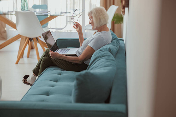 Senior woman using laptop while sitting at home - Foto, imagen