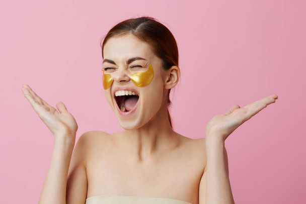 Nuori nainen laastaria nuorentaminen ihonhoito hauskaa suihkun jälkeen vaaleanpunainen tausta - Valokuva, kuva