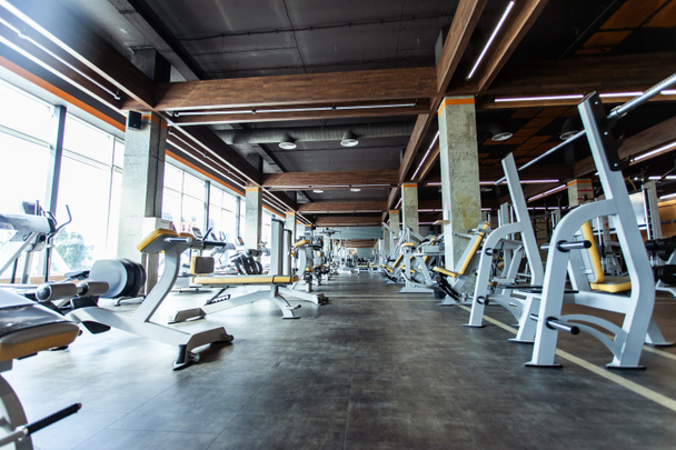 Interior moderno del gimnasio con equipos de fitness y máquinas de ejercicio. Pabellón deportivo con grandes ventanales - Foto, imagen