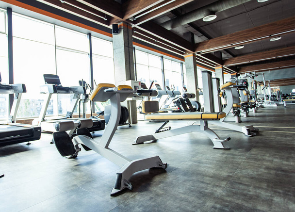 Interior moderno ginásio com equipamentos de fitness e máquinas de exercício. Salão de esportes com grandes janelas - Foto, Imagem