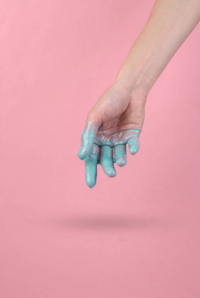 Human hand with dripping turquoise paint on a pink background. Minimal creative layout. Concept art - Фото, зображення