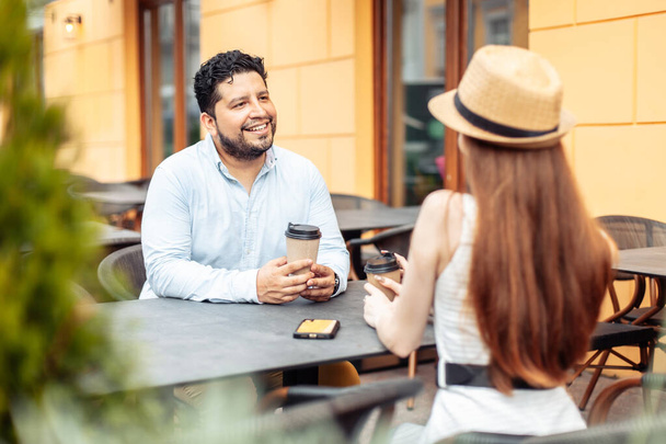 Casal internacional apaixonado bebendo café enquanto sentado à mesa no café ao ar livre - Foto, Imagem