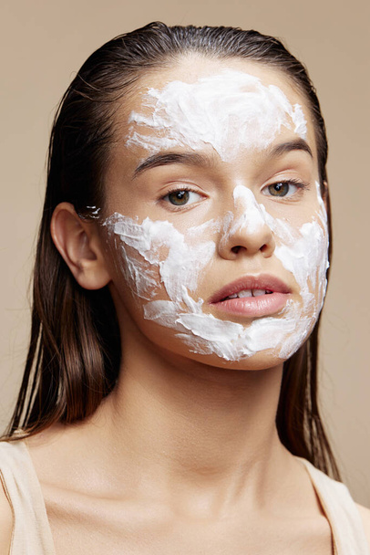 Πορτρέτο Γυναίκα εφαρμογή μια καταπραϋντική μάσκα προσώπου φροντίδα του δέρματος μπεζ φόντο - Φωτογραφία, εικόνα