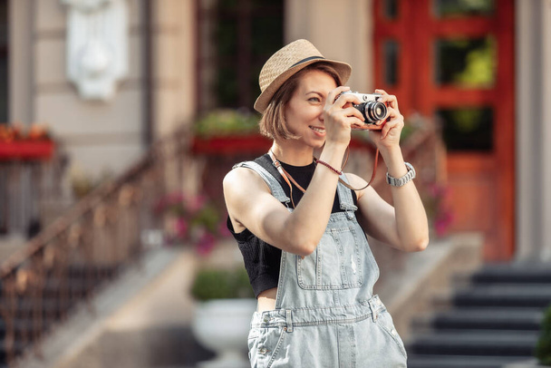 young hipster woman in denim overalls with retro camera in the city - Foto, Imagem