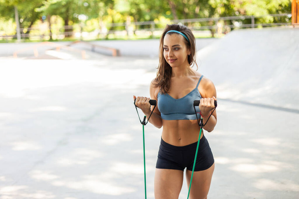 Mladá atletka cvičí venku s gumovým expandérem. Zdravý životní styl - Fotografie, Obrázek