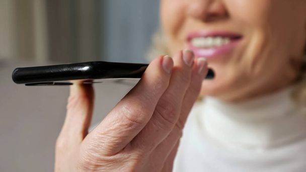 Mujer de mediana edad habla a través de teléfono inteligente utilizando altavoz - Foto, imagen
