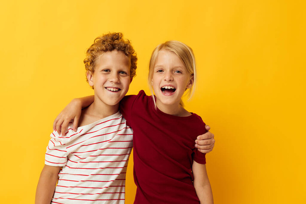 picture of positive boy and girl standing side by side posing childhood emotions yellow background - Φωτογραφία, εικόνα